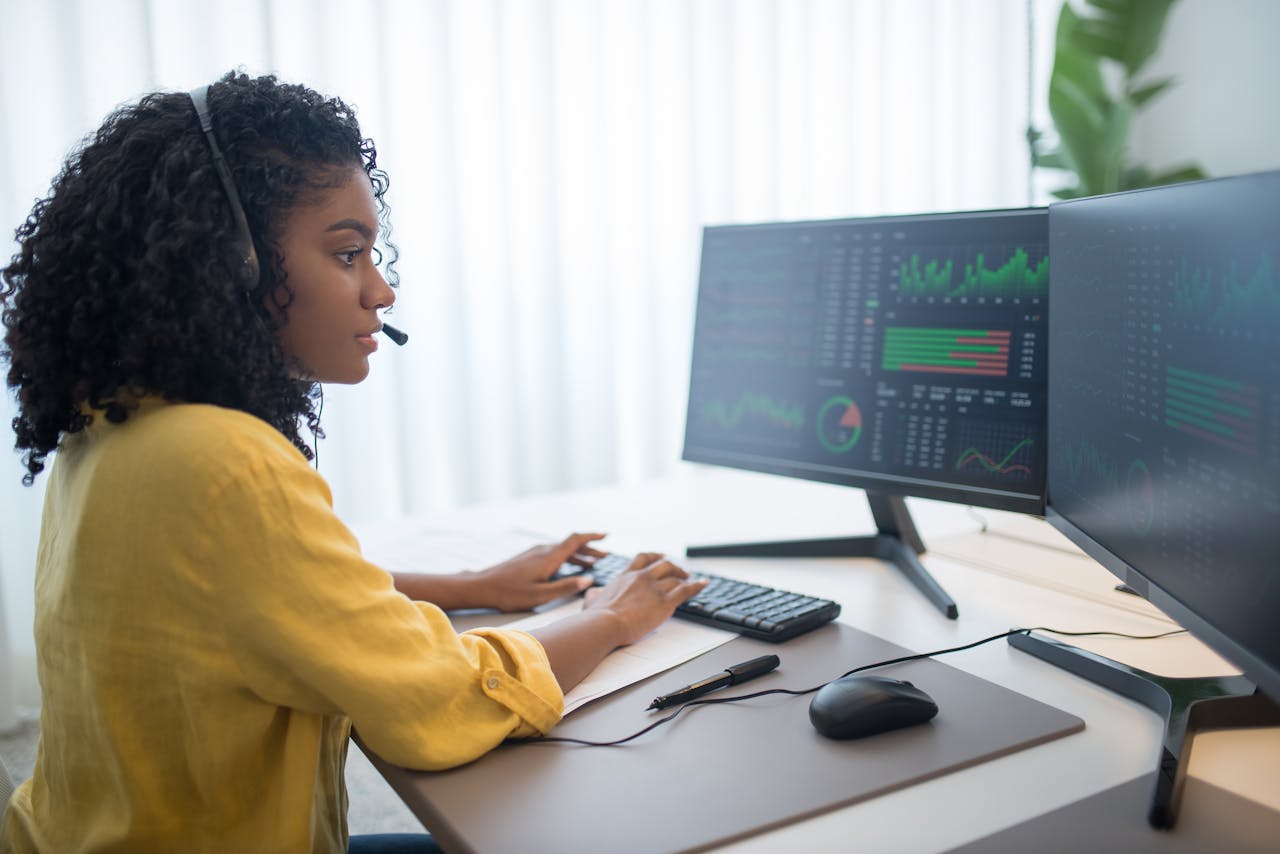 services-img African American woman working in office analyzing data on dual computer monitors.